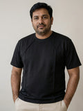 Man wearing a structured black t-shirt with improved fit around chest and midsection”